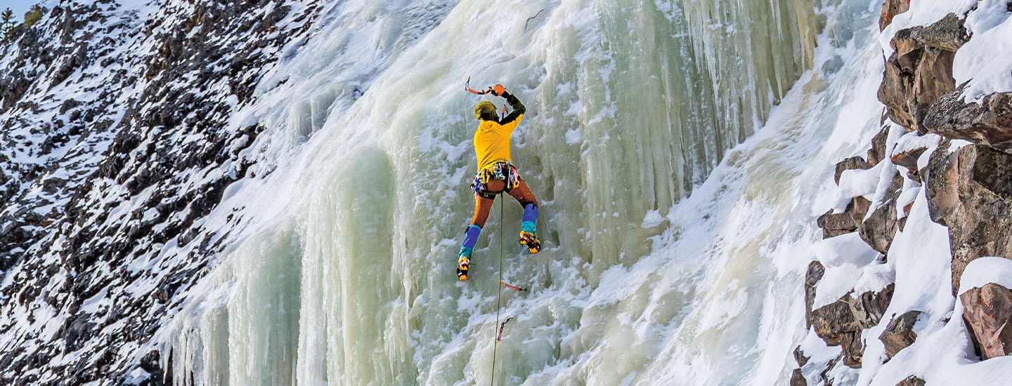 Photo of a person ice climbing on the side of a mountain