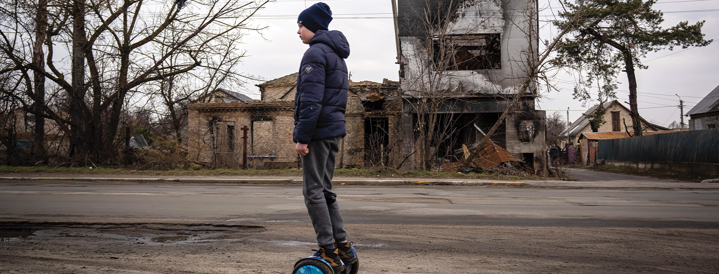 Photo of a kid using a hoverboard while destroyed buildings sit in the background