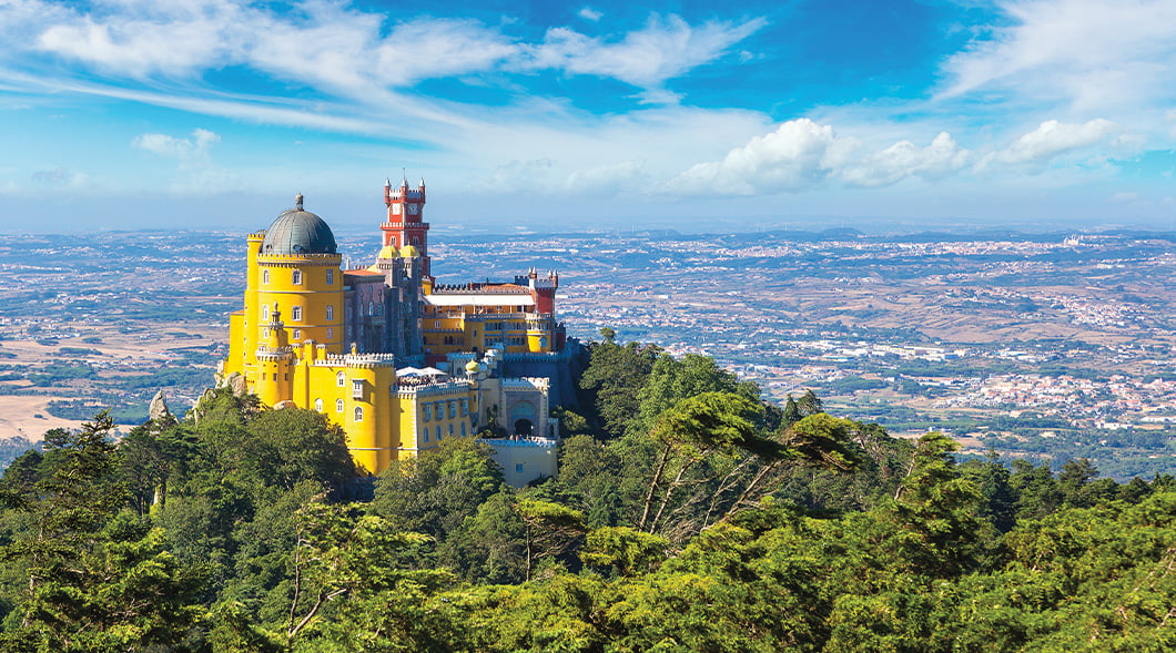 Photo showing a beautiful colorful castle on a mountain with a city below