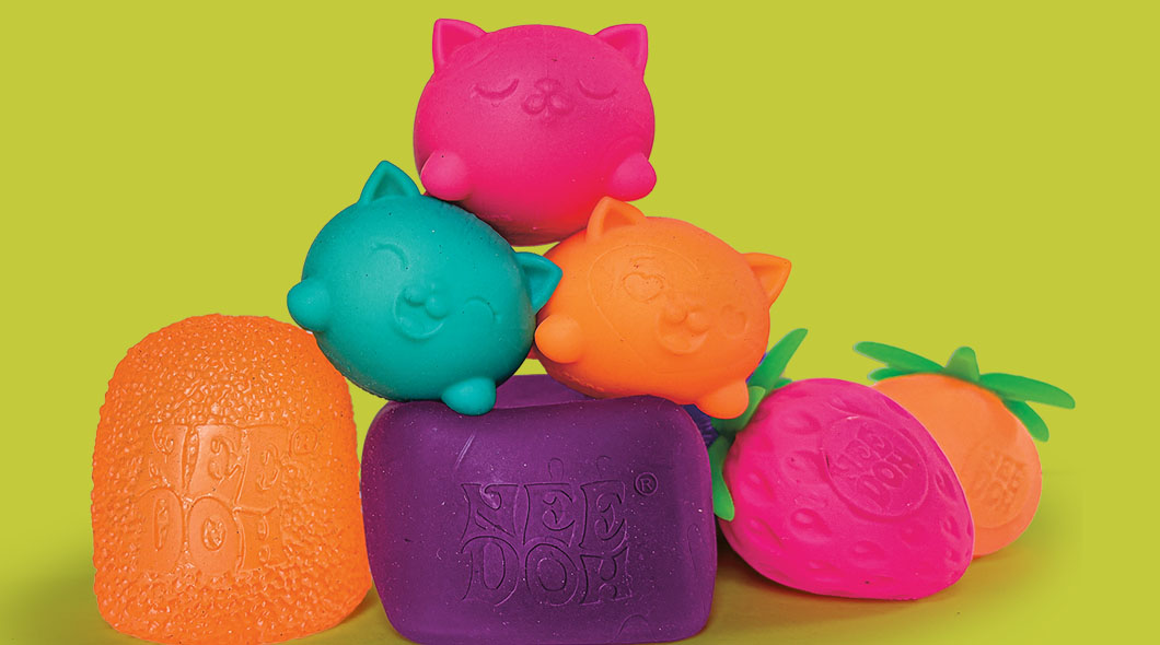 A collection of colorful Nee Doh squishy toys in cat and fruit shapes stacked together