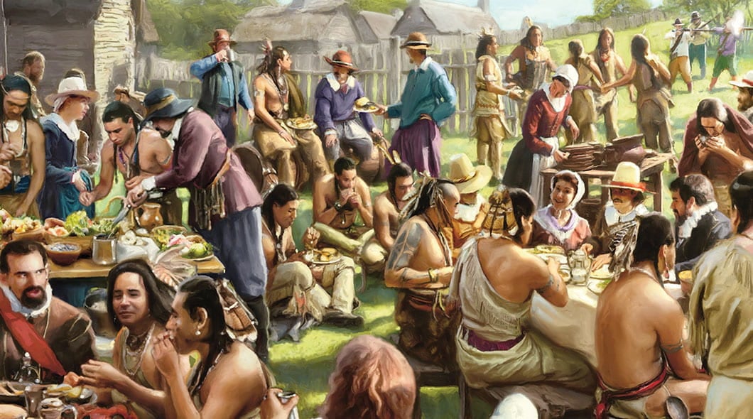 A large gathering of Native Americans and colonial settlers share a meal outdoors near a wooden fort